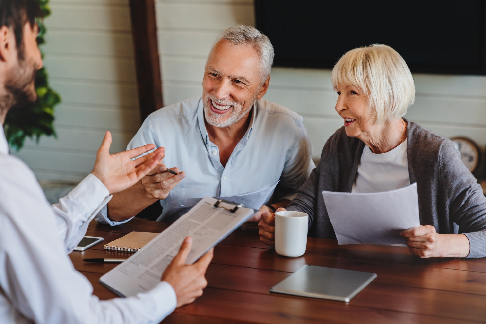 Happy aged couple consulting with insurance agent at home